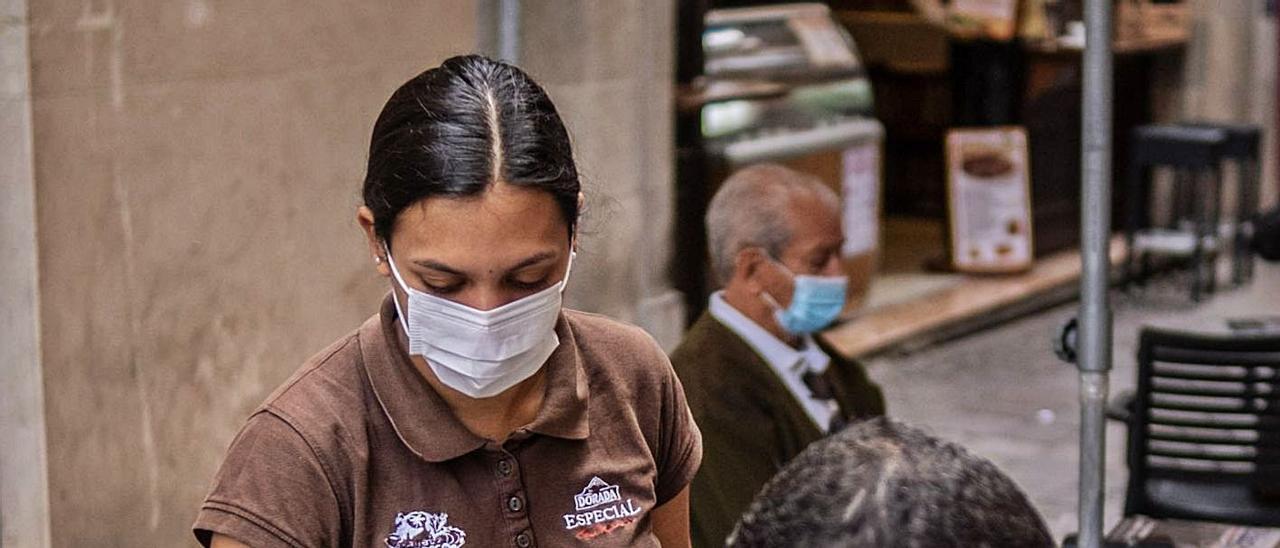 Una camarera sirve a un cliente en una terraza debido al cierre del interior del local en nivel 3.  | | ANDRÉS GUTIÉRREZ