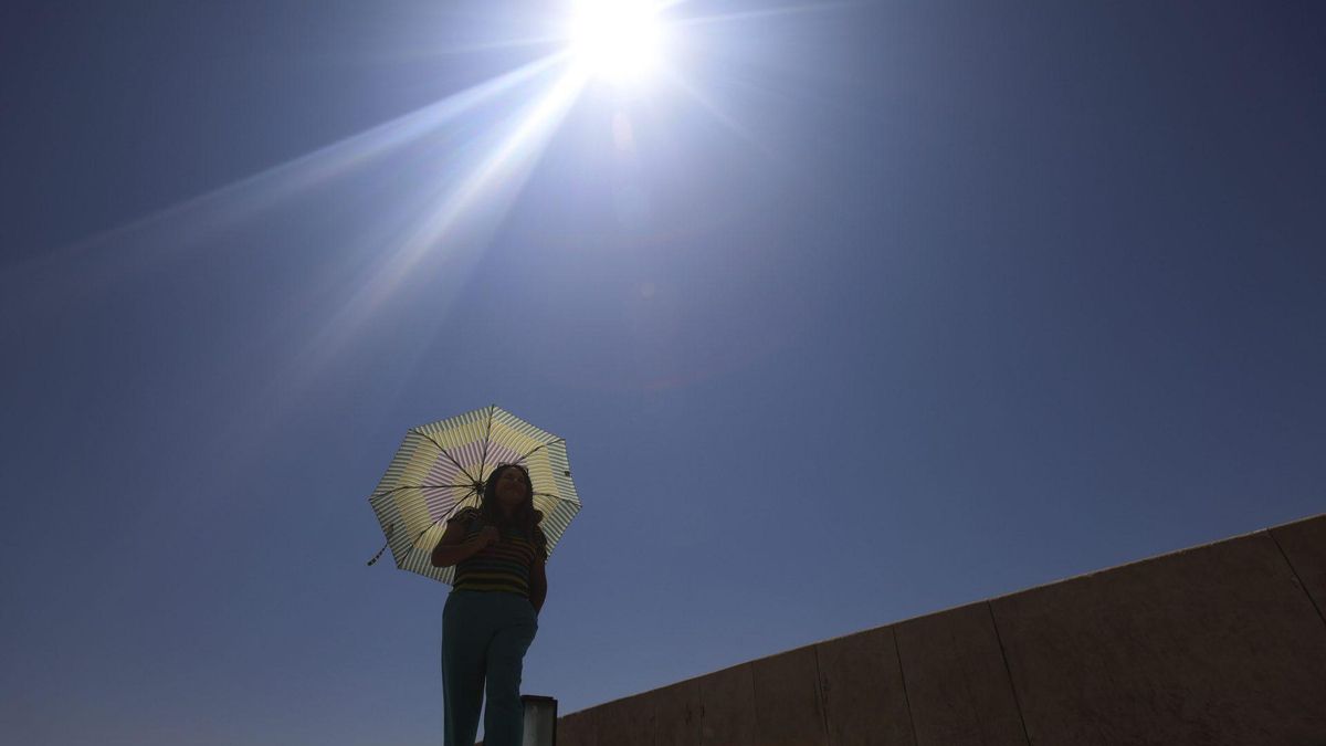 Una mujer se protege del calor con un paraguas - Imagen de archivo
