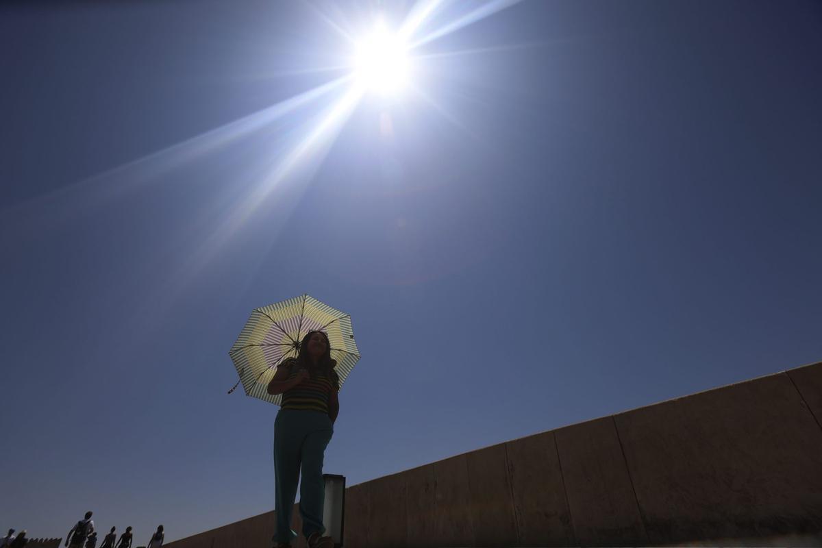 Una mujer se protege del calor con un paraguas.