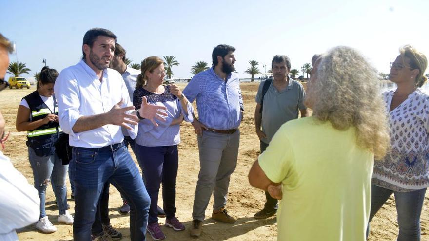 Pedro García, de espaldas, charla con miembros del Gobierno regional en la playa donde han aparecido los peces muertos.