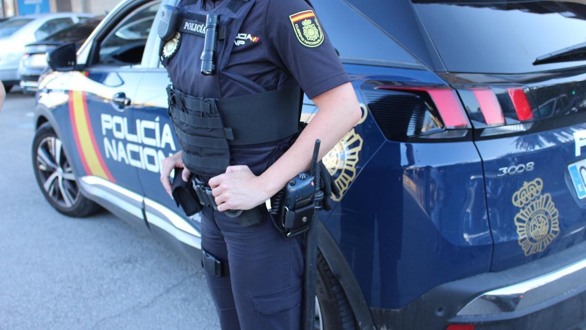 Una agente de la Policía Nacional, junto a un coche patrulla.