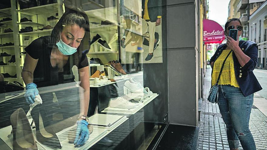 Una mujer prepara el escaparate de una tienda de calzado en Santa Cruz de Tenerife.