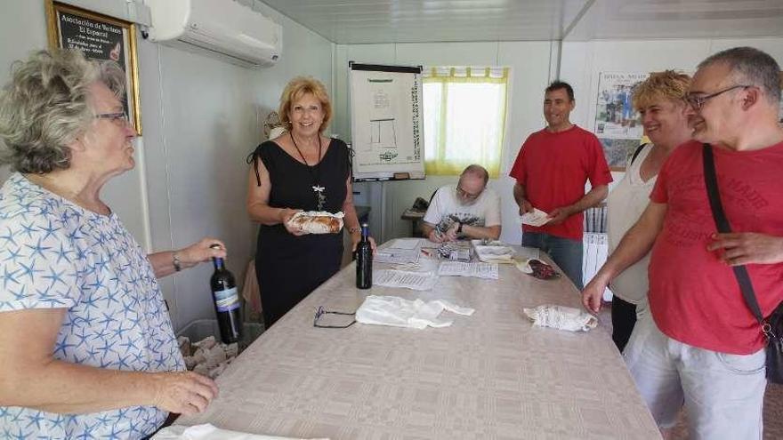 Arriba, preparativos para la comida popular en Arnao; debajo, el reparto de bollos y vino en San Juan de Nieva.