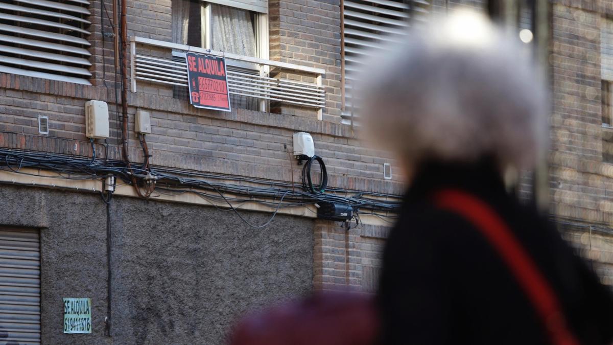 Una mujer pasa por delante de un cartel de un piso en alquiler, en Murcia.