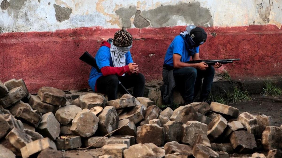 Miembros de las fuerzas gubernamentales sentados sobre lo que queda de las barricadas destruidas en el barrio de Monimbo