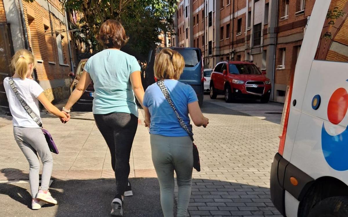 Las menores, con la madre de una de ellas, junto al transporte escolar. | LNE