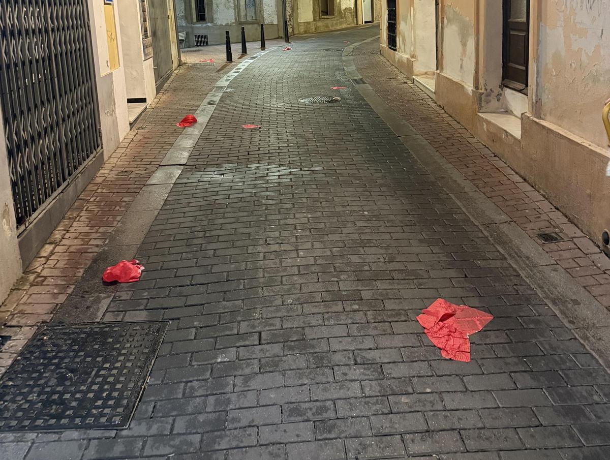 Restos de varios farolillos aparecen esparcidos por el pavimento tras la lluvia y las rachas de viento del miércoles.