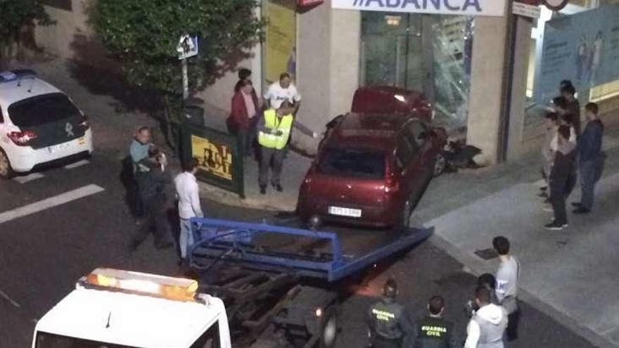 El coche se empotró en la puerta de entrada a Abanca. // Muñiz