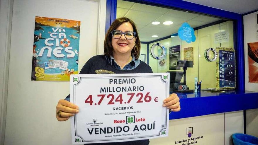 Rocío Cores, propietaria de la Librería Xesteira, muestra el cartel con el premio de la Bonoloto. // Iñaki Abella