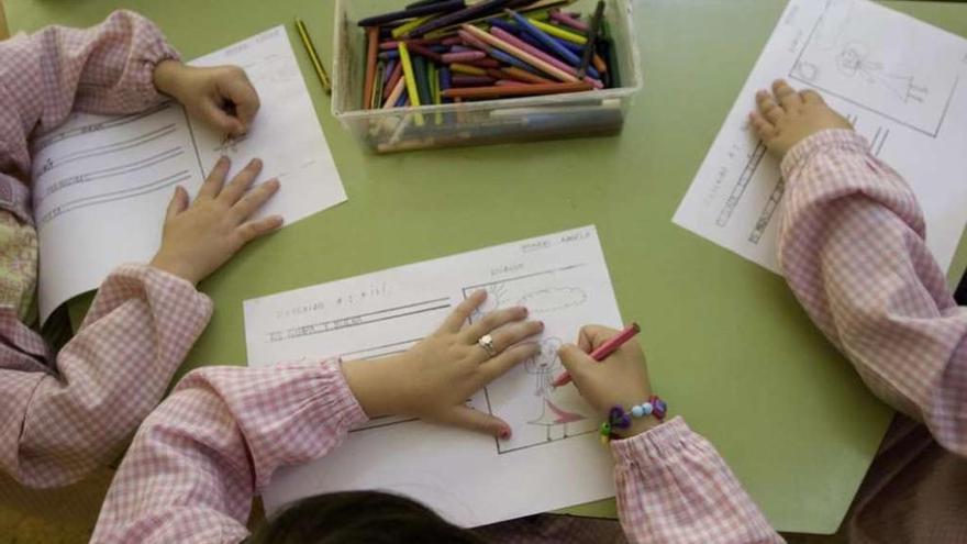 Un grupo de niños de corta edad rellenando fichas escolares en una clase de infantil.