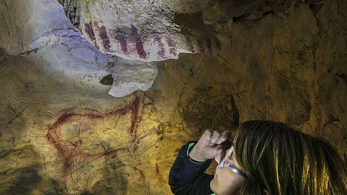 La experta María González- Pumariega observa la cierva de El Pindal, con el craquelado por encima.