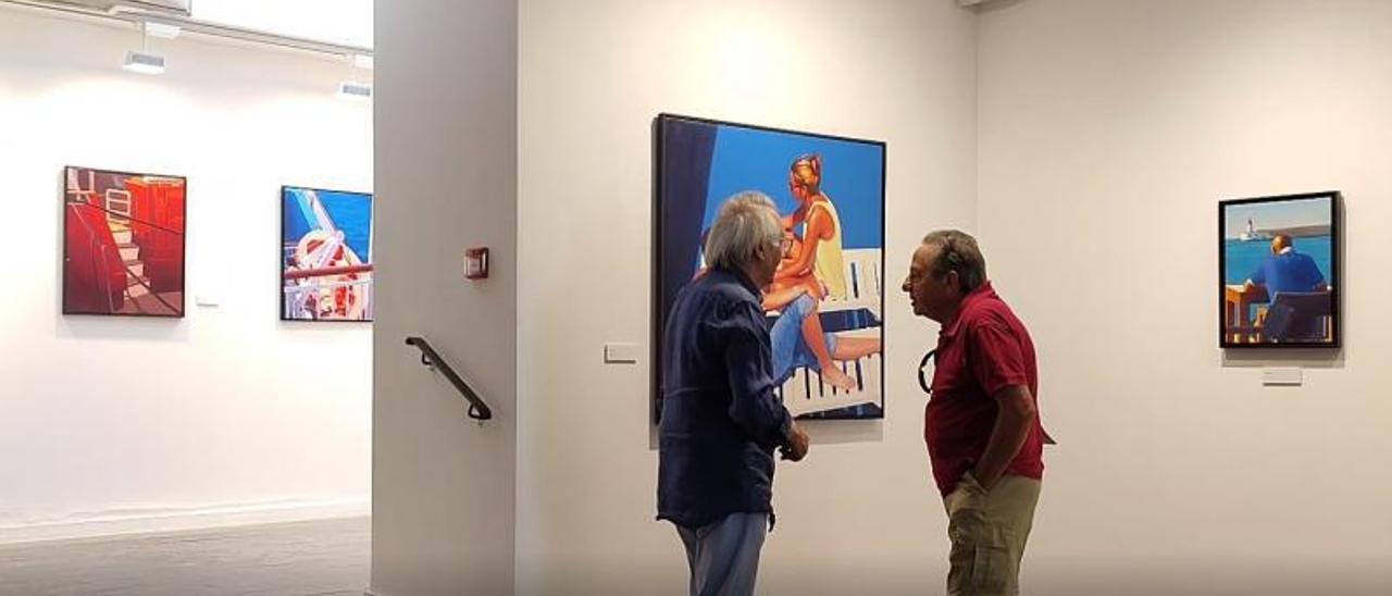 José María Cuasante conversa con un hombre con sus obras de fondo.