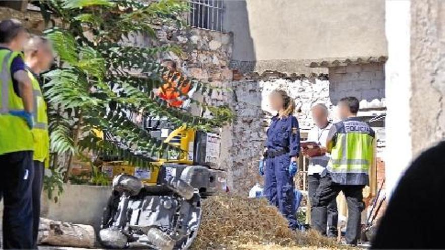 Miembros del dispositivo policial junto a la excavadora en el patio en el que estaba el cadáver.