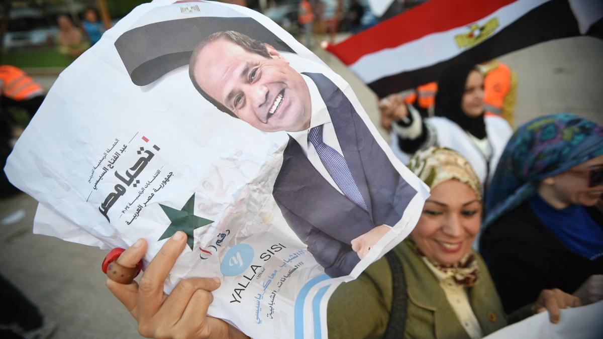 Una mujer sostiene una foto del presidente egipcio Abdel Fattah al-Sisi mientras la gente celebra los resultados de las elecciones presidenciales en El Cairo.