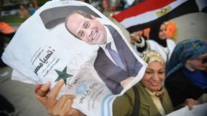 Una mujer sostiene una foto del presidente egipcio Abdel Fattah al-Sisi mientras la gente celebra los resultados de las elecciones presidenciales en El Cairo.
