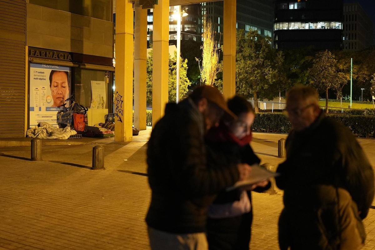 Tres voluntaris a prop de dues persones sense llar, en una imatge d’arxiu.