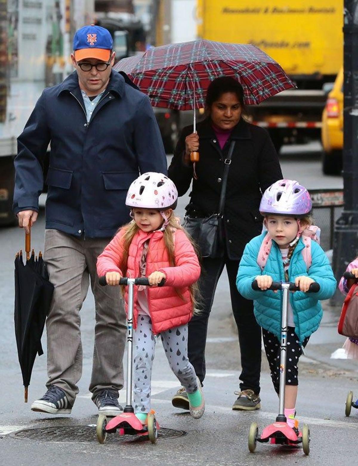 Las pequeñas Tabitha y Marion van con su patinete delante de su padre