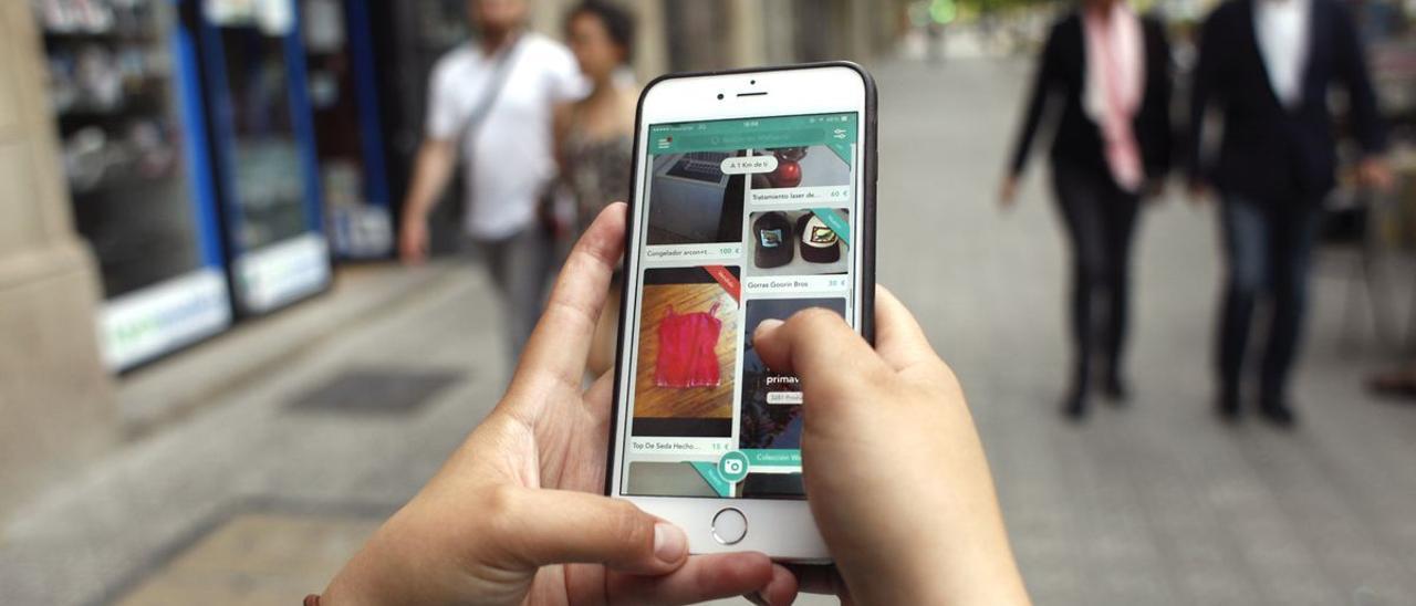 Una usuaria consulta en su móvil una aplicación de compra-venta de productos de segunda mano.