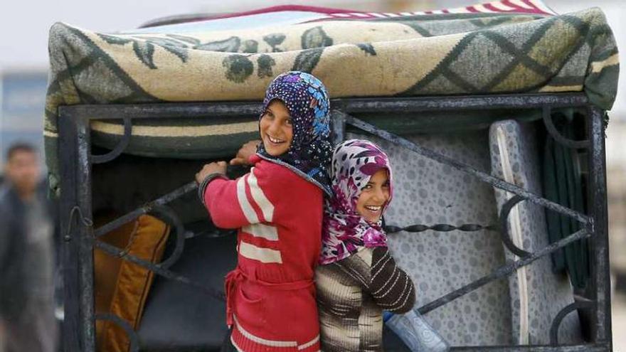 Dos niñas sirias, subidas a un camión, en el paso de Bab al Salama.  // Reuters