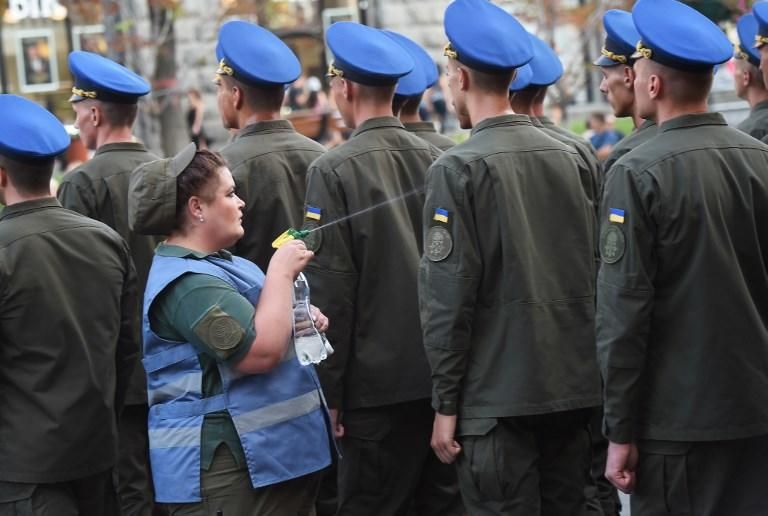 Una enfermera militar rocía a los militares ucranianos con agua para enfriarlos del calor durante un ensayo de desfile en el centro de Kiev, antes de las celebraciones del Día de la Independencia de Ucrania el 24 de agosto.