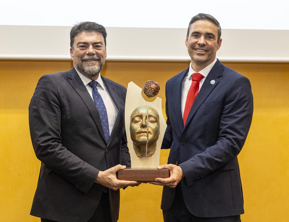 El alcalde Luis Barcala junto a Moreno del Val sostienen la réplica de la escultura "Somos uno" que se ha usado también para dar forma a estos premios