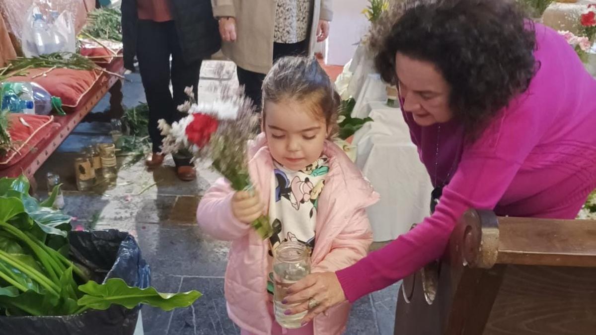 La pequeña Martina recibe la ayuda de la hermana mayor, Leonor Muñiz, para colocar las flores.