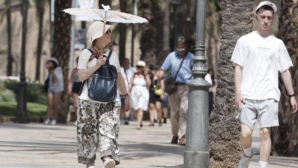 Una mujer combate el sol y el calor con una sombrilla en Palma.