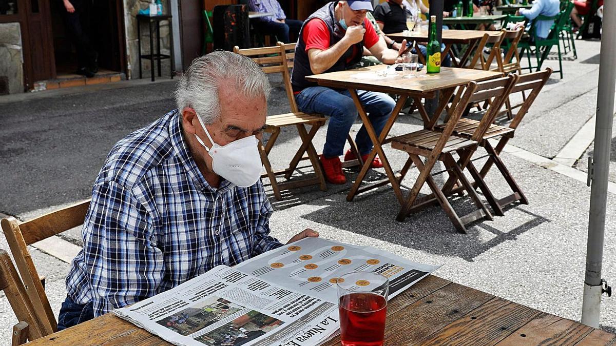 Un hombre lee La Nueva España en una terraza de la plaza Requejo, en Mieres, en una fotografía de archivo. | Juan Plaza