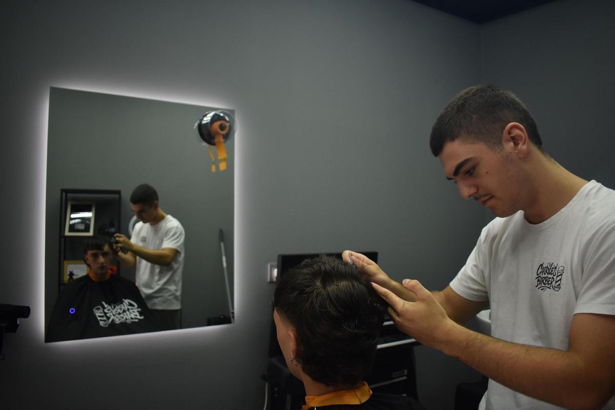 Alberto Carriles, cortando el pelo a un cliente en su barbería de Arriondas.