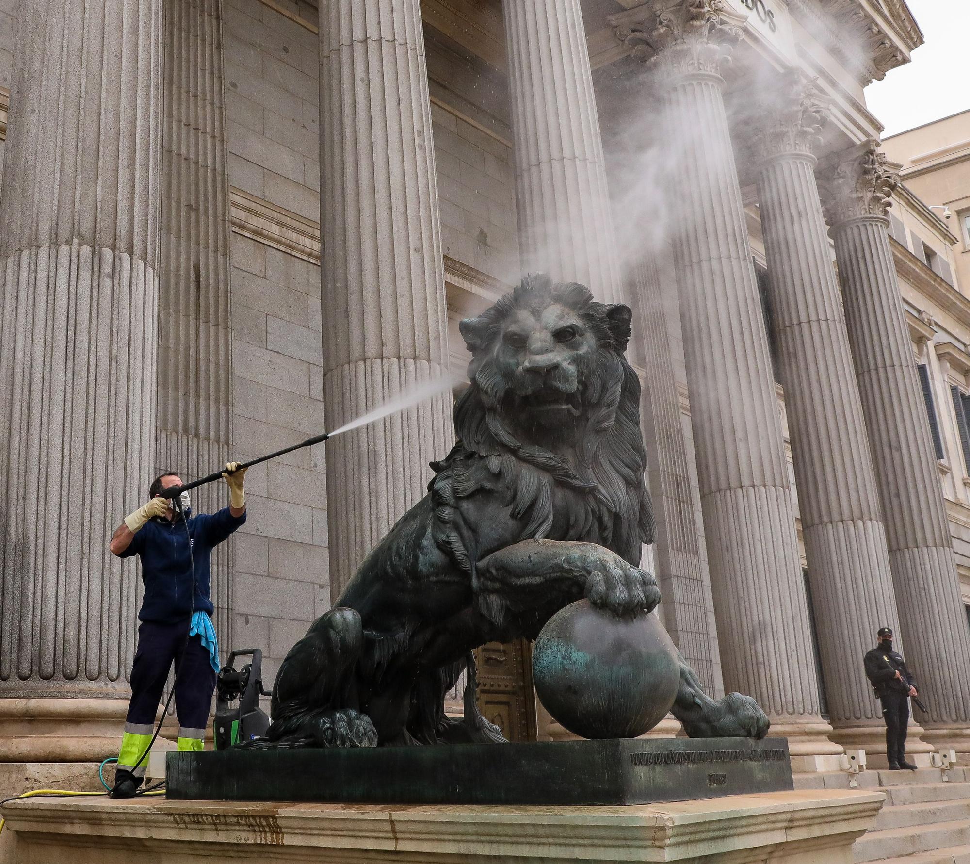 Un trabajador limpia el león del Congreso, cubierto de polvo sahariano, este martes en Madrid.
