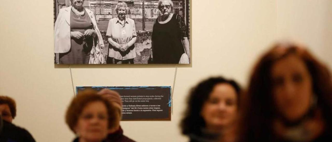 Al fondo, sobre las cabezas de los participantes en la visita a la exposición, una foto de Anita Sirgo, Celestina Marrón y Eufrasia Albes.