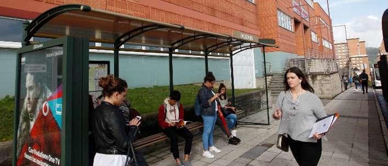 Estudiantes esperando el autobús junto a la Facultad de Derecho del campus universitario del Cristo.