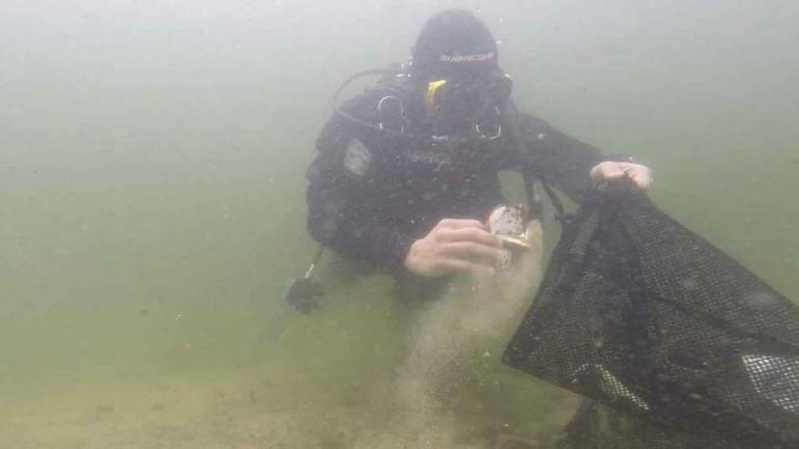 Imagen submarina de uno de los buzos recogiendo basura del fondo del Lago de Sanabria.