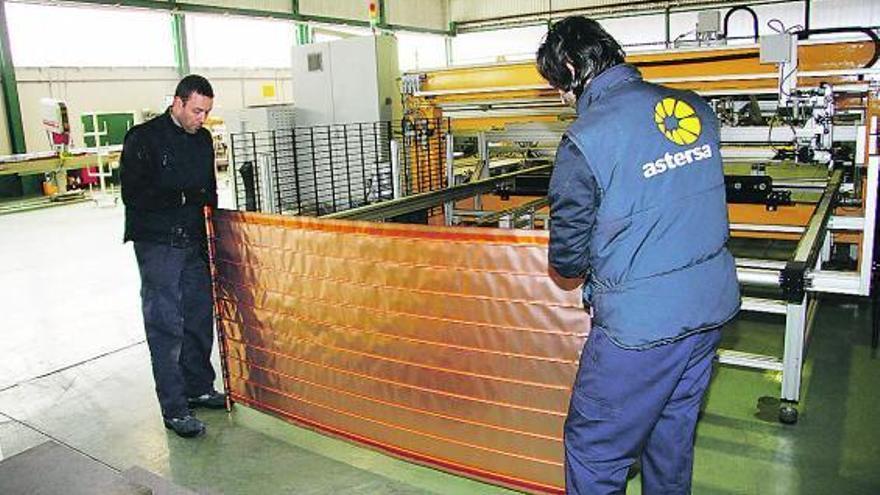 Dos trabajadores montan un panel solar en la fábrica de Astersa en Mieres.