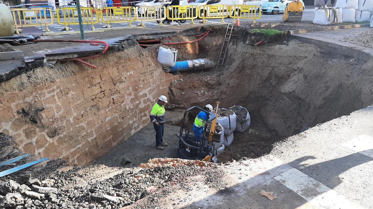 Operarios de Emaya en el interior del socavón, junto a la muralla y sobre la capa de hormigón con la que se ha repuesto el colector de agua residual dañado.