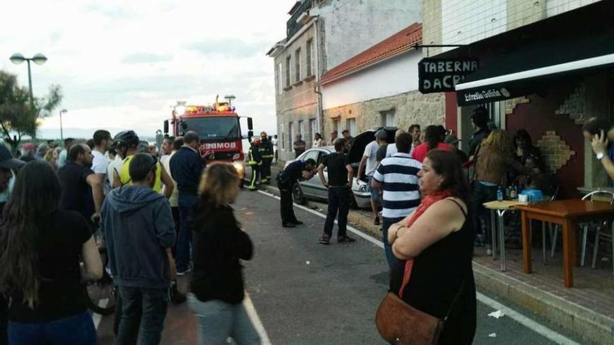 Las personas que se encontraban en el lugar de los hechos y el coche que invadió la acera. // Muñiz