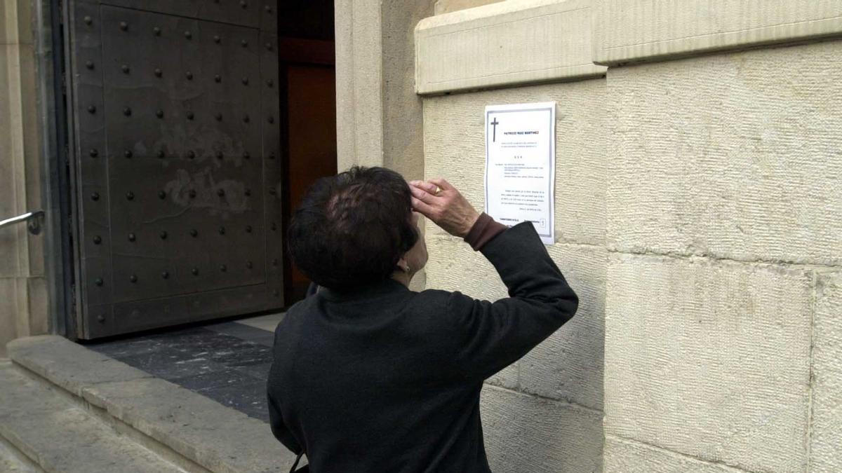 Una mujer viendo una esquela en la puerta de una iglesia de Elche, en imagen de archivo