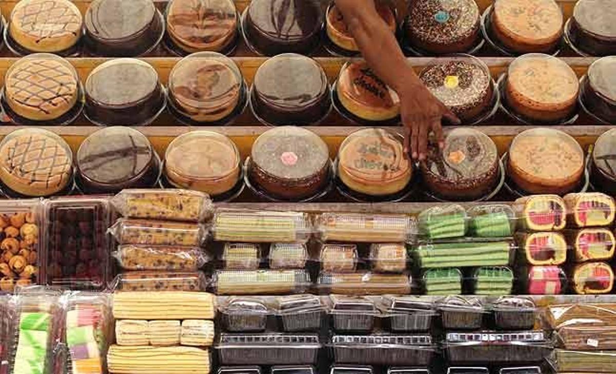 Un venedor agafa un pastís per posar-lo a la venda en un carrer de Kuala Lumpur (Malàisia).
