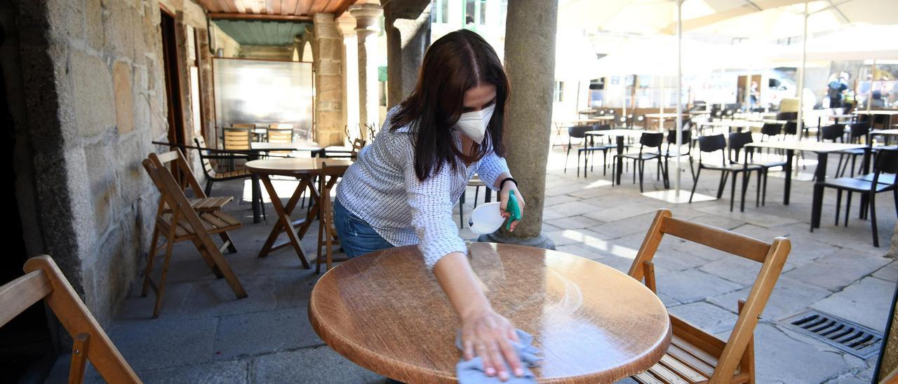 Una trabajadora desinfectando la terraza de un bar. // Gustavo Santos