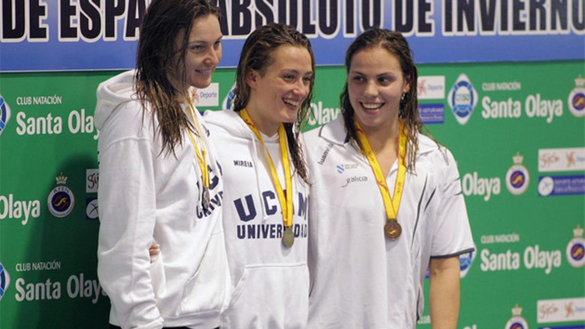 Las nadadoras Mireia Belmonte (centro) y Melani Costa (izquierda) y Maria Vilas tras imponerse primera, segunda y tercera clasificada, respectivamente, en la prueba de 800 metros estilos, de los Campeonatos de España de piscina corta que se celebraro