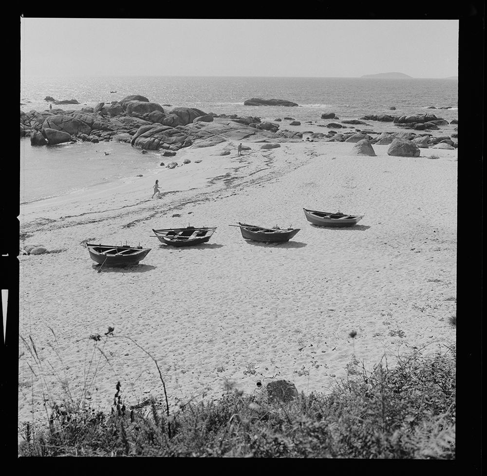 Pontevedra. Playas de San Vicente. La Toja [Paisaje de playa donde hay 4 barcas de pesca en la arena. Dos mujeres caminan por la arena] 1967.jpg