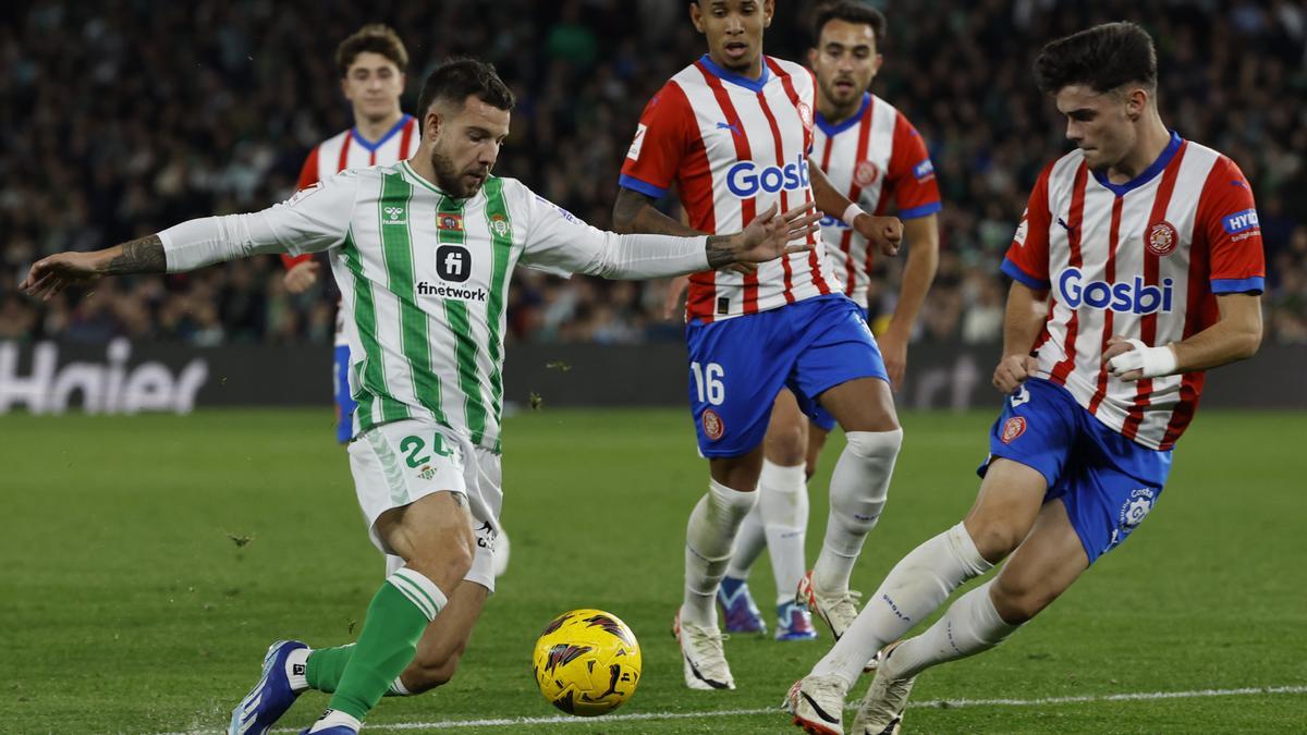 Aitor Ruibal lucha con Sávio Moreira de Oliveira y Miguel Gutiérrez, ambos del Girona FC, durante el encuentro correspondiente a la jornada 18 de LaLiga que Real Betis y Girona FC juegan hoy jueves en el estadio Benito Villamarín, en Sevilla.