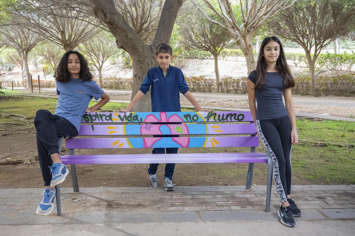 Alumnado del IES Los Tarahales, junto al banco cuyo diseño representa a su centro educativo.