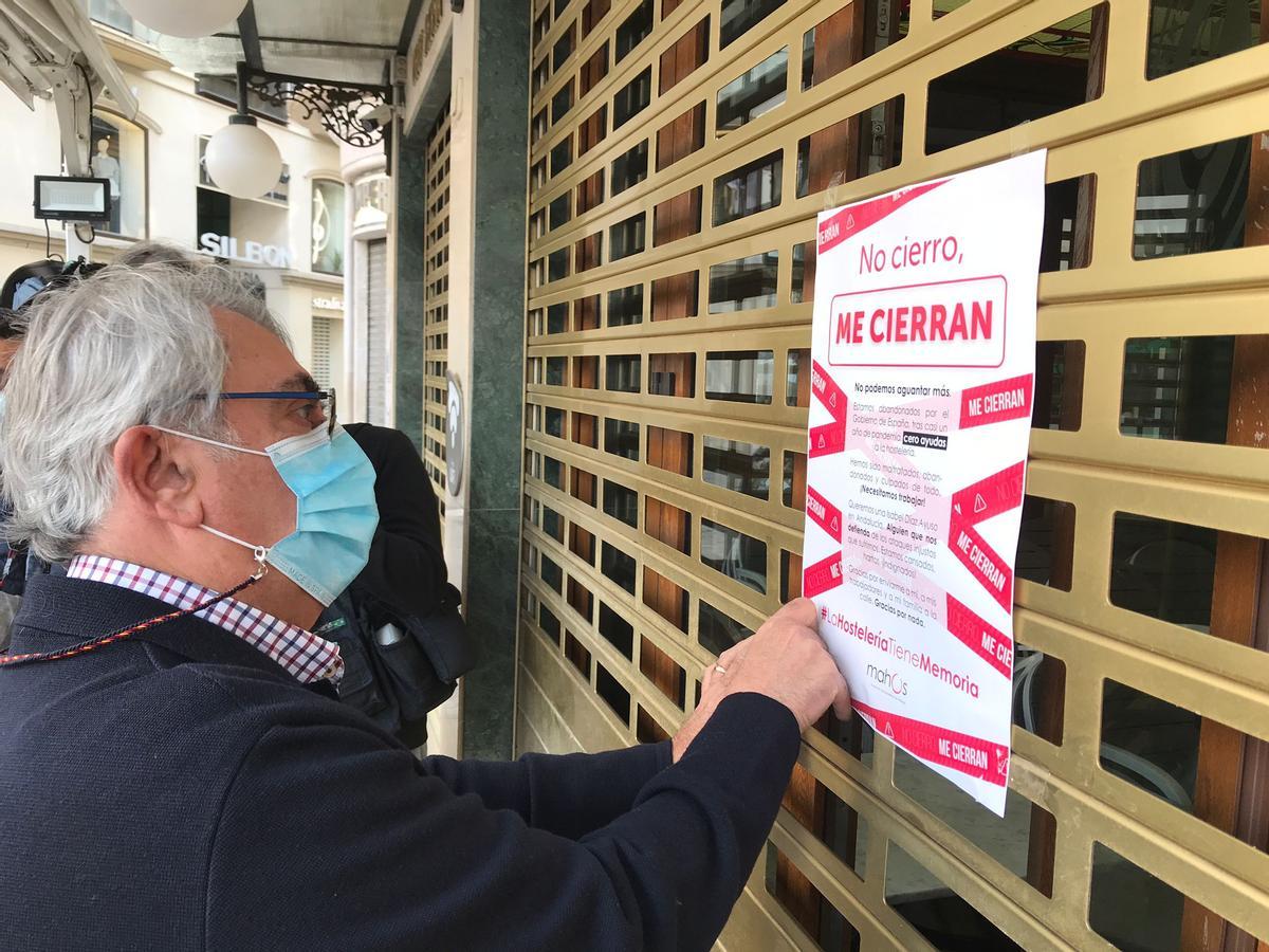 El empresario Rafael Prado coloca un cartel en la puerta del Café Central