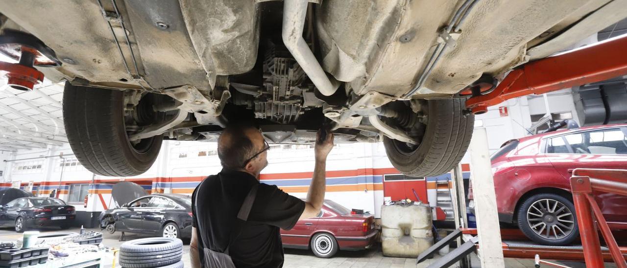 Ariza, mecánico en un taller de Zaragoza, revisa el catalizador de un automóvil situado en la parte frontal del mismo.  | ANDREEA  VORNICU