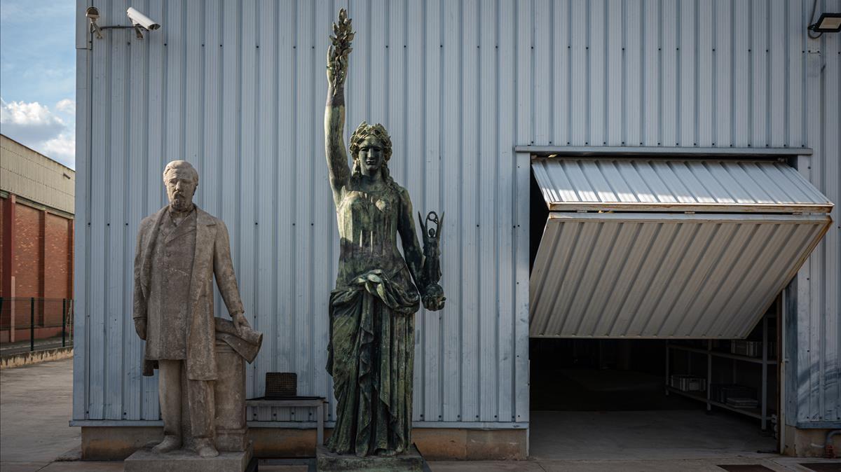 La estatua de Antonio López, a la intemperie en un almacén municipal, junto a otra figura maldita, la Victòria de Frederic Marès.