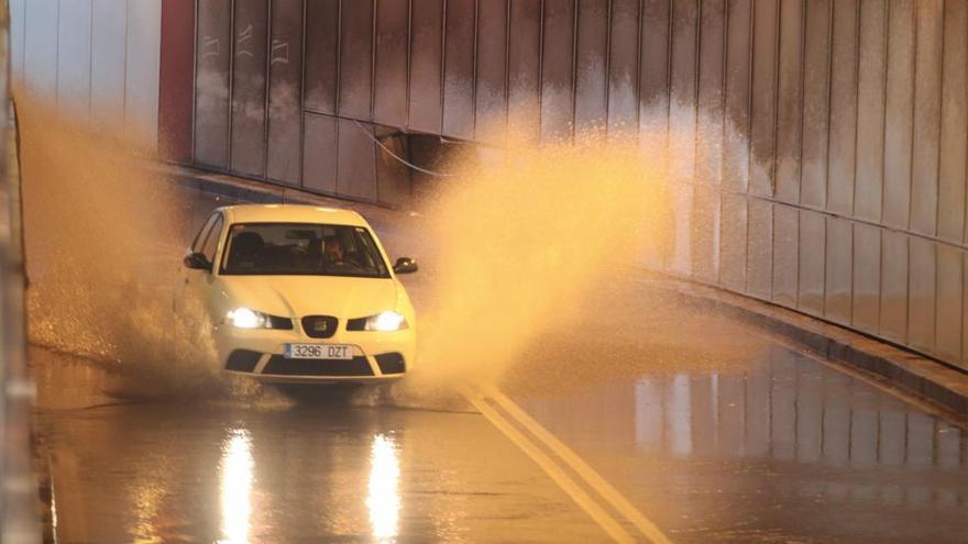 Un coche levanta agua al pasar por el túnel que comunica La Calzada y Tremañes