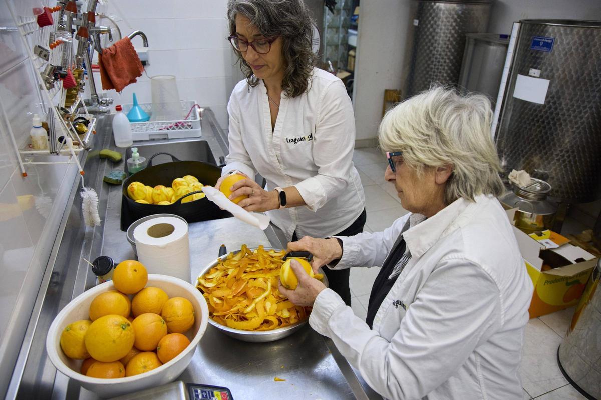 Judith Ramírez i Amparo Ardanuy pelant taronges per a produir un dels licors de Traguinyol.