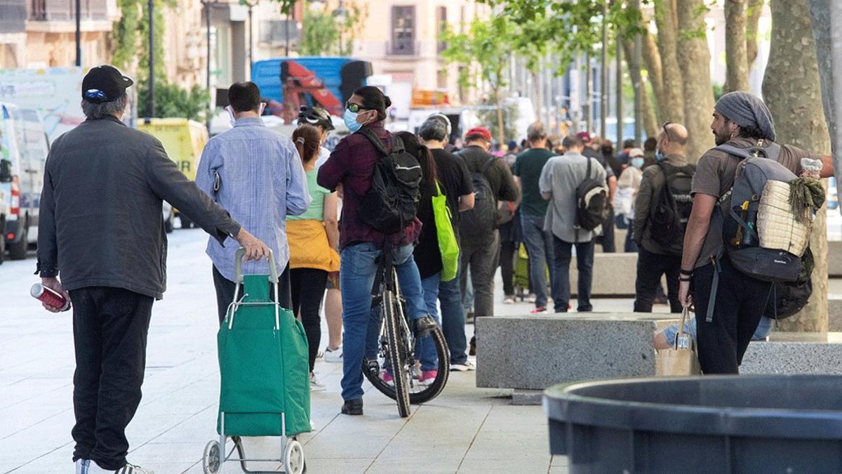 Una larga cola de personas esperan para recoger comida en la parroquia de Santa Anna de Barcelona, el 18 de mayo