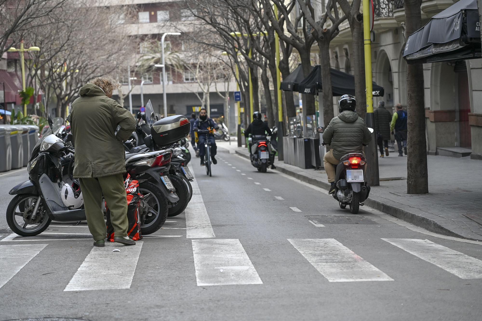 Dos motocicletas utilizando el carril bici para descender por la calle Tuset